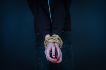 Young girl with bound hands on black background. Woman violence concept