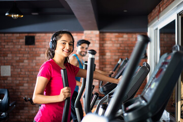 Asian Indian young Couple doing cardio training program in gym or fitness club