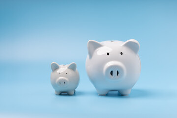 A family white piggy banks on blue background with copy space. Concept savings, investment, save money in the future.