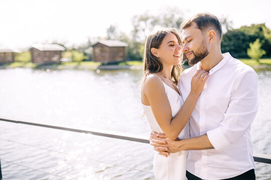 Young man and woman spend time together walking along the pier on the river.