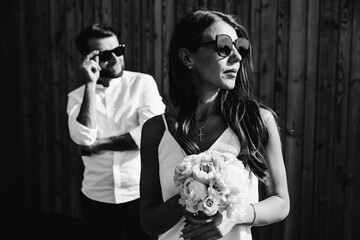 Black and white photo of the bride and groom on a wooden background. stylish newlyweds with glasses. wedding day.