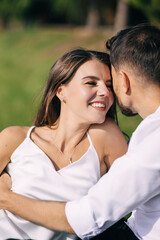 Fototapeta premium Happy young couple laying in grass on summer day. Man and wife newlyweds relaxing in sunny park after wedding.
