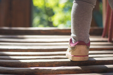 Close up little feet of child on walking in white sneakers. Summer first steps on green bokeh background. Selective and soft focus