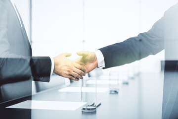 Handshake of two businessmen on boardroom interior background, deal and trading concept....