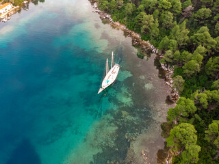 Aerial view of a wooden sailing boat anchored in a small picturesque harbor. Amazing Greek beauty...