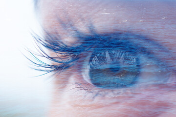 Double exposure with macro feminine blue eye and calm wavy water of ocean or sea. Concept of...