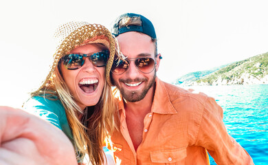 Young happy couple in love taking selfie at sailboat excursion with water camera - Boat trip life...