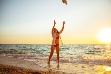 Beautiful woman resting in the beach at the evening against the sunset in ocean