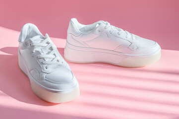 
White sneakers on a pink background.