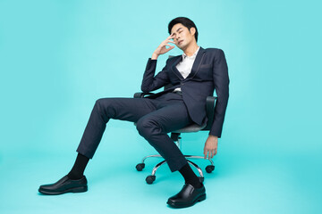 Young Asian businessman exhausted and frustrated sitting on chair office isolated on green...
