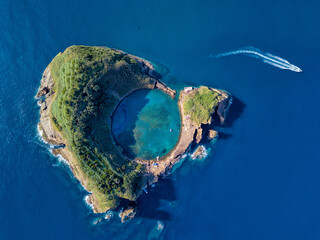Obraz premium Azores aerial panoramic view. Top view of Islet of Vila Franca do Campo. Crater of an old underwater volcano. San Miguel island, Azores, Portugal. Heart carved by nature. Bird eye view.