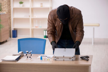 Young man in balaclava stealing vaccine from the lab