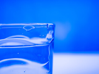part of a glass of water on a blue background. close-up