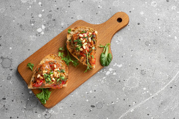Bruschetta caponata with pine nuts decorated with a leaf of basil.