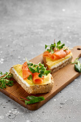 Bruschetta with salmon. Whole grain bread with salmon, cheese on a wooden board.