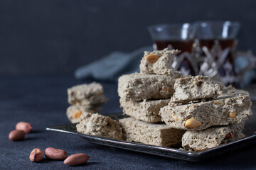 Sweet sunflower halva with peanut on metal tray on dark gray background.