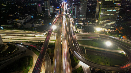 Fototapeta na wymiar Aerial view of the city traffics at the Jakarta at night. Vehicles are moving on the road between buildings. Jakarta, Indonesia, May 4, 2021
