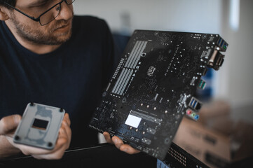 portrait of a handsome nerd man is servicing Computer motherboard and cooler.