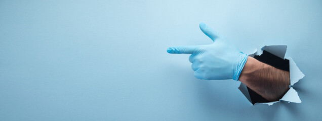 Man's hand points a finger in a glove on a blue background