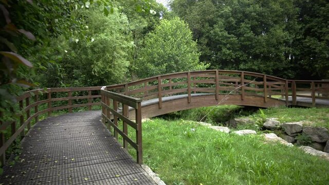 brown wooden bridge in the middle of nature on a path to cross a river. rural structure for ecological trail. country road with decorative wooden walkways.