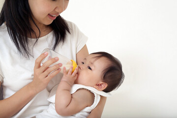 白背景で赤ちゃんに哺乳瓶で授乳する姿のクローズアップ。愛情、赤ちゃん,赤ちゃん,乳幼児、育児イメージ