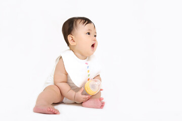 白背景でお座りする女の子の赤ちゃん。成長,健康,元気,育児イメージ