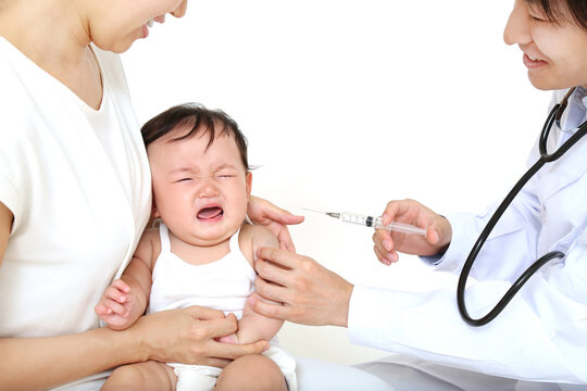 白背景で注射をされ泣く新生児。予防接種イメージ
