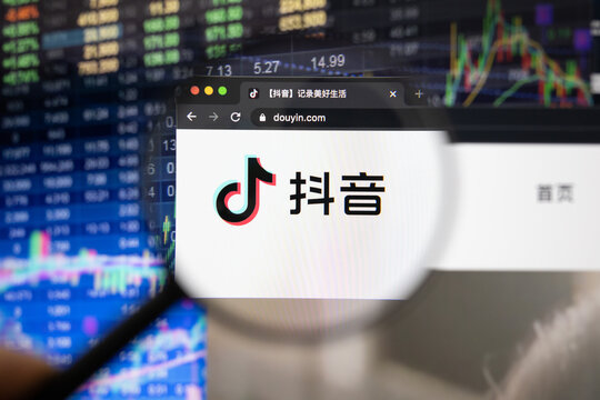 Douyin, the Chinese version of TikTok, company logo on a website with blurry stock market developments in the background, seen through a magnifying glass