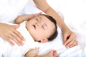 寝ている赤ちゃんに優しく手で触れる母さんの手のクローズアップ。育児、母子、愛情イメージ