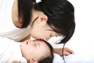 Obraz na płótnie Canvas 昼寝する赤ちゃんの額にキスするお母さん。母性、愛情イメージ