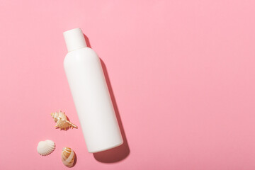 White cosmetic bottle with face cream or lotion and telana against a pink background with...