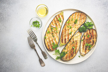 Grilled eggplant slices, garnished with fresh herbs, on white background, top view