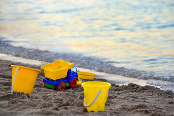 Fototapeta na wymiar Plastic children toys on the seashore at sunset