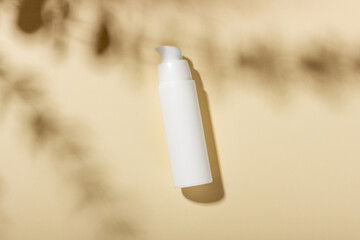 White bottle of moisturizing face and body cream with shadows on the background. Cosmetic spa product