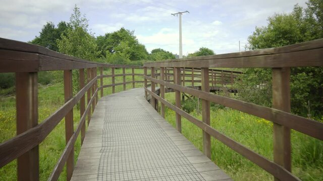 brown wooden bridge in the middle of nature on a path to cross a river. rural structure for ecological trail. country road with decorative wooden walkways.