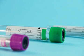 vacuum tubes for collection and blood samples on blue background..Transparent with purple and green lid. Label to identify the data. Selective focus.
