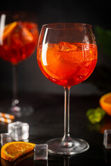 Aperol spritz cocktail in glass with fresh orange on dark background