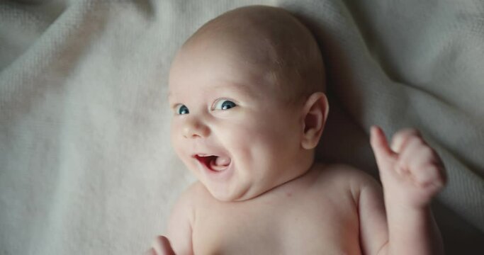 Cute baby smiling and looking in the camera close up. Little kid funny smiling, lying at the back
