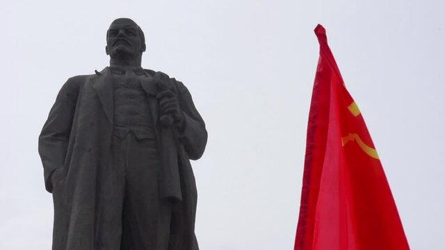 Monument to Vladimir Lenin end soviet flag flying.
