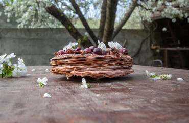 cake of chocolate thin pancakes with cherries and curd cream