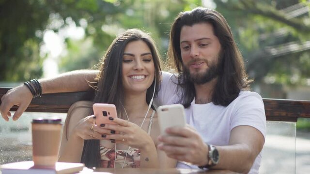 Beautiful couple using cell phone and looking at screen together outdoors. 