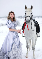 Fototapeta na wymiar Beautiful woman in traditional dress standing with white horse in winter field