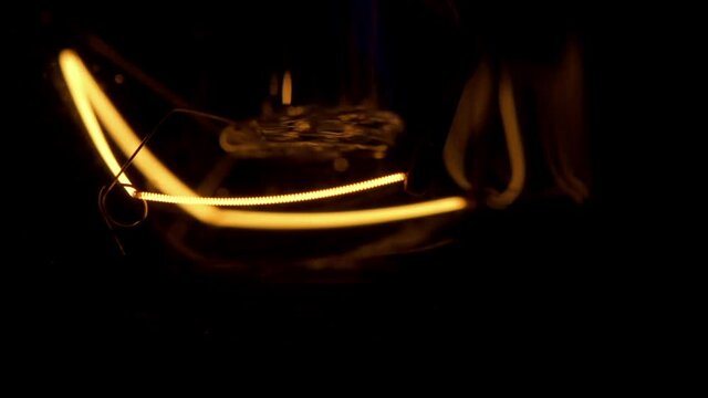 Real light bulb turning on, flickering and turning off. Incandescence thread, close up. Loop.
