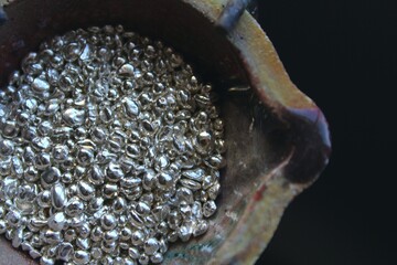 A ceramic crucible or melting pot with grains of sterling silver 925 for jewelry making after hand smelting in a workshop. One of the two major precious metals on the market.