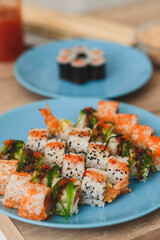Still life plates with Japanese sushi rolls over white wooden table. Vertical food background for sushi and rolls menu