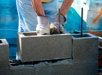 Construction site: building wall of concrete block.
Mason in laying concrete blocks

