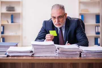 Old businessman employee unhappy with excessive work in the office