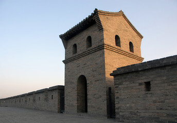 Pingyao in Shanxi Province, China. Pingyao city wall with a watchtower seen from the wall ramparts in the evening sun.