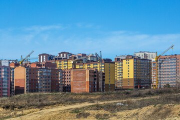 Extensive scaffolding providing platforms for work in progress on a new apartment block,Tall building under construction with scaffolds,Freestanding tower crane on a building site