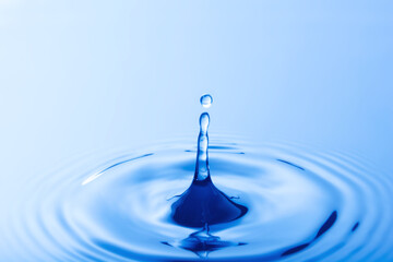 Drop of water. Water droplet falling impact with water surface. causing rings on water surface..